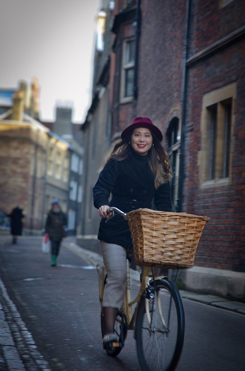 A woman cycling on a vintage bike with a basket