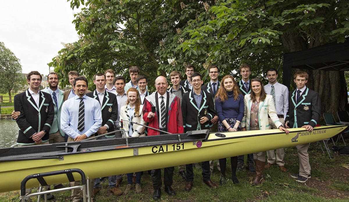 A group of people in blazers standing behind a rowing boat