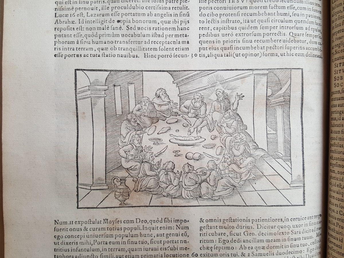 A page in a 16th-century printed book, with Latin text in two columns and a large woodcut illustration depicting a round table where the Last Supper of Jesus is under way.